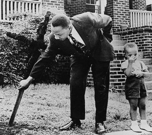 1960, Martin Luther King Jr removing a KKK burned cross from his lawn with his son